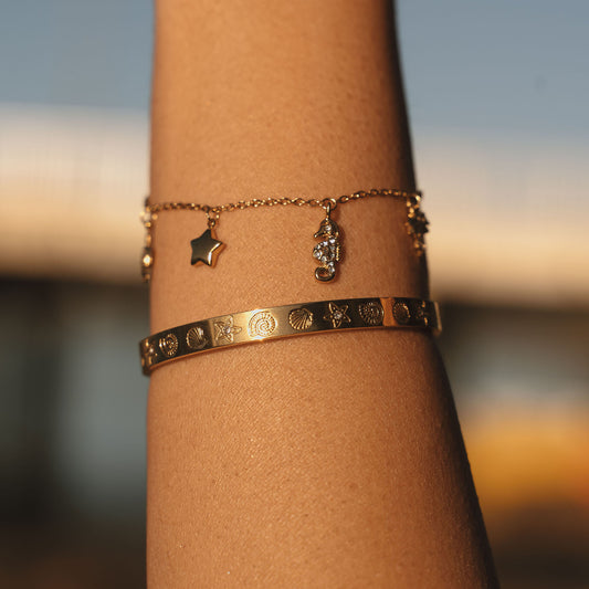 Gold bracelet with various ocean charms on a white background. Turtle, Star, seahorse, Palm tree, shell and fish charms. Stainless steel 18k PVD Gold Plated. Waterproof jewellery. Australian jewellery. ocean inspired jewellery