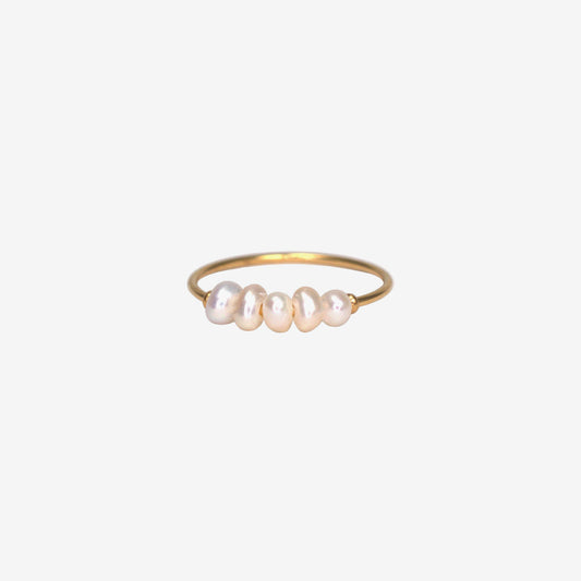 Gold ring with pearls on a light gray background